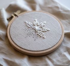 an embroidered snowflake is displayed on a piece of fabric