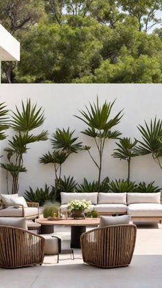 an outdoor living area with couches, chairs and tables in front of a white wall