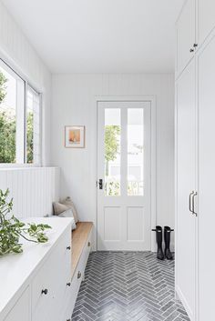 a white kitchen with herringbone tile flooring