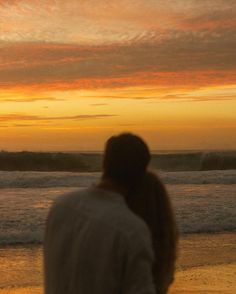 a person walking on the beach at sunset