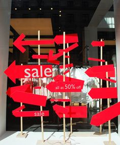 several red signs are in front of a store window that says sale all at 50 % off