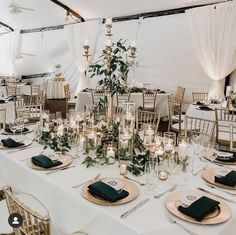 the tables are set with candles and place settings for an elegant wedding reception in a marquee