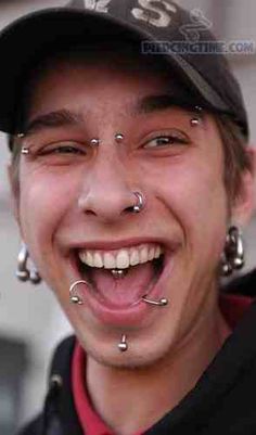 a man with piercings on his nose smiles