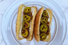 two hot dogs with peppers and mustard on a plate