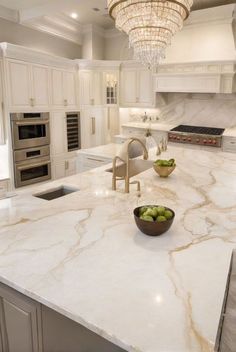 a large kitchen with marble counter tops and an island in front of the stove top