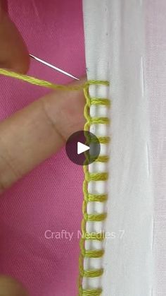 someone is working on the side of a piece of fabric with yellow thread and scissors