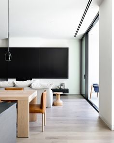 an instagram photo of a living room and dining area with white walls, wood flooring and black accents