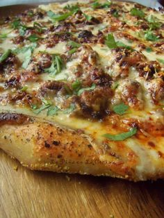 a close up of a pizza on a cutting board with cheese and meat toppings