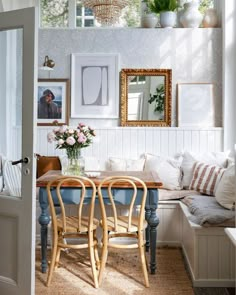 a dining room table and chairs in front of a window with pictures on the wall