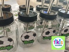 several mason jars with soccer themed lids and straws in them are sitting on a table