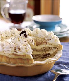 a pie sitting on top of a wooden table next to a cup and saucer