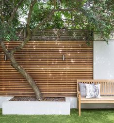 a wooden bench sitting under a tree next to a fence