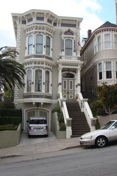 two cars are parked in front of a large house with many windows and balconies