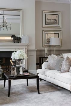 a living room with white furniture and gray accents on the walls, along with an ornate coffee table