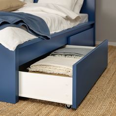 a bed with an open drawer underneath it on top of a carpeted floor next to a wall