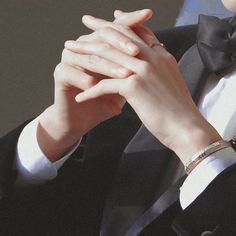 a man in a tuxedo holding his hands together