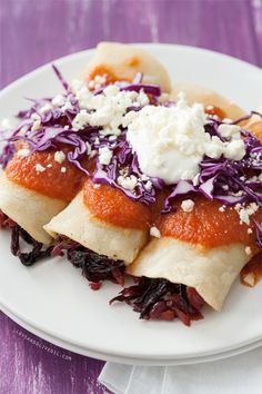 some food is on a white plate with purple and red cabbages, cheese and sauce