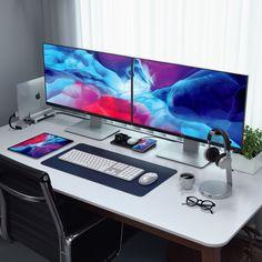 two computer monitors sitting on top of a desk next to a keyboard and monitor screen