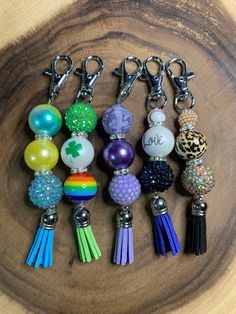 several key chains with charms attached to them sitting on a wooden surface next to a ruler