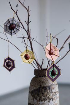 a vase with some branches in it and decorations hanging from the top, on a table