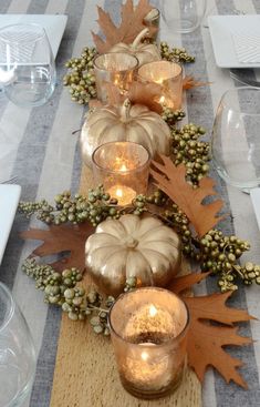 a table topped with candles and fall leaves