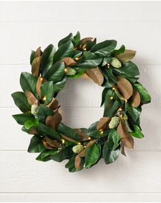 a green wreath with lights hanging on the side of a white brick wall in front of a wood paneled wall