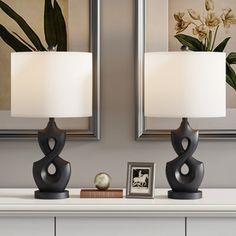 two lamps sitting on top of a white dresser next to a framed photo and an old baseball