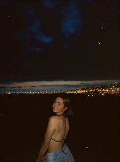 a woman standing in the dark looking at the sky