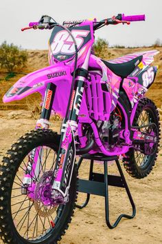 a pink dirt bike parked on top of a metal stand