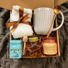 an open box with honey, tea and other items in it sitting on a blanket