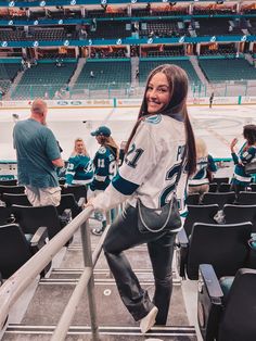 a woman standing on the bleachers at a hockey game