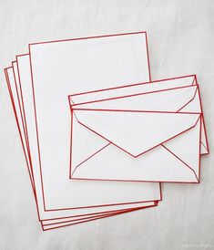 four envelopes lined up on top of each other with red paper sticking out of them