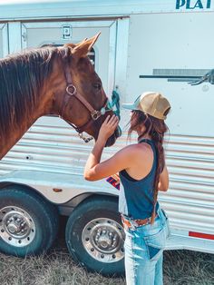 a woman standing next to a horse in front of a trailer