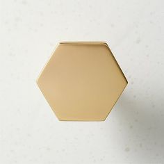 a gold hexagonal object on a white surface