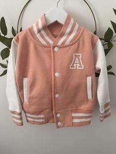 Looking for the perfect personalised custom kids varsity jacket?  Our supersoft, college baseball children's varsity jacket is the ultimate blend of style and comfort. With its letterman style design, it's a must-have for kids, toddlers and babies alike.  Featuring a name on the back and initial on the front, our jacket allows you to add a personal touch that your child will love.  It's the ideal birthday, new baby, or Christmas gift. Plus, with the option to match siblings, you can create adora Fall School Varsity Jacket With Letter Print, Fall Letter Print Varsity Jacket For School, Cotton Varsity Jacket With Letter Patch And Baseball Collar, College Cotton Varsity Jacket With Letter Patch, Varsity Outerwear With Ribbed Cuffs For School, Varsity Style Outerwear With Ribbed Cuffs For School, Cotton Varsity Jacket With Letter Patch, White Varsity Outerwear With Letter Patch, School Varsity Jacket With Ribbed Cuffs