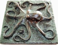 an octopus sculpture sitting on top of a green tile wall mounted plaque in the shape of a square