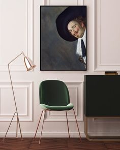 a green chair sitting in front of a painting on the wall next to a lamp