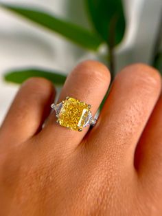 a woman's hand holding a yellow diamond ring