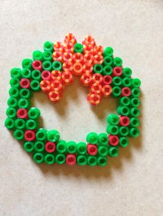 a green, red and orange brooch sitting on top of a table