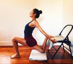 a woman is doing yoga in front of a chair