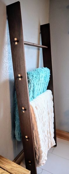 a wooden ladder leaning against the wall next to a white bed with blue blankets on it