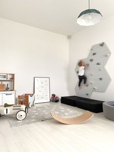 a child climbing on a rock wall in a playroom with toys and bookshelves