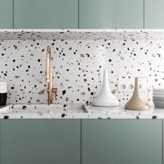 three vases are sitting on the counter in front of a wall with black and white speckles