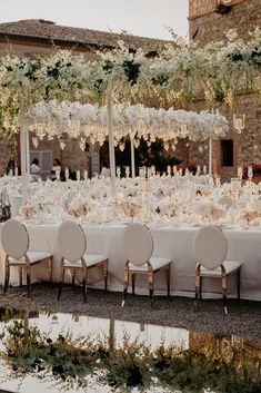 the tables are set up with white linens and floral centerpieces on them