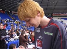 a young man signing autographs for fans in the stands at an indoor sporting event