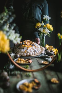 a table topped with lots of food on top of a wooden table next to flowers