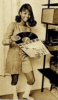 an old black and white photo of a woman holding a record in front of a tv