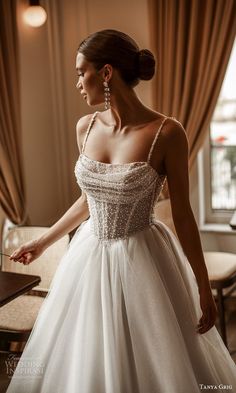 a woman in a white dress is standing near a table and looking at the window