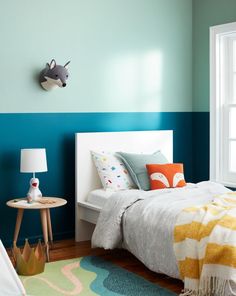 a bedroom with blue and green walls, white bedding and colorful rugs on the floor