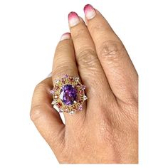 4.25 Carat Oval Cut Amethyst Sapphire Rose Gold Cocktail Ring  This beautiful vintage inspired setting with a modern colorful theme has an Oval Cut Amethyst weighing 3.33 carats and is surrounded by 20 Round Cut Multi-Colored Sapphires that weigh 0.92 Carats. The total carat weight of the ring is 4.25 Carats. The ring is made in 14 Karat Rose Gold and weighs approximately 5.5 grams. The ring is a size 7  Exact dimensions for this item are unknown. Please reach out in the seller Q&A for any quest Oval Purple Amethyst Ring With 17 Jewels, Purple Oval Ruby Ring, Fine Jewelry, Oval Purple Gemstones, Exquisite Oval Purple Ring, Heirloom Multi-stone Purple Amethyst Ring, Formal Purple Oval Ruby Ring, Heirloom Multi-stone Oval Amethyst Ring, Heirloom Oval Multi-stone Amethyst Ring, Fine Jewelry Oval Multi-stone Amethyst Ring